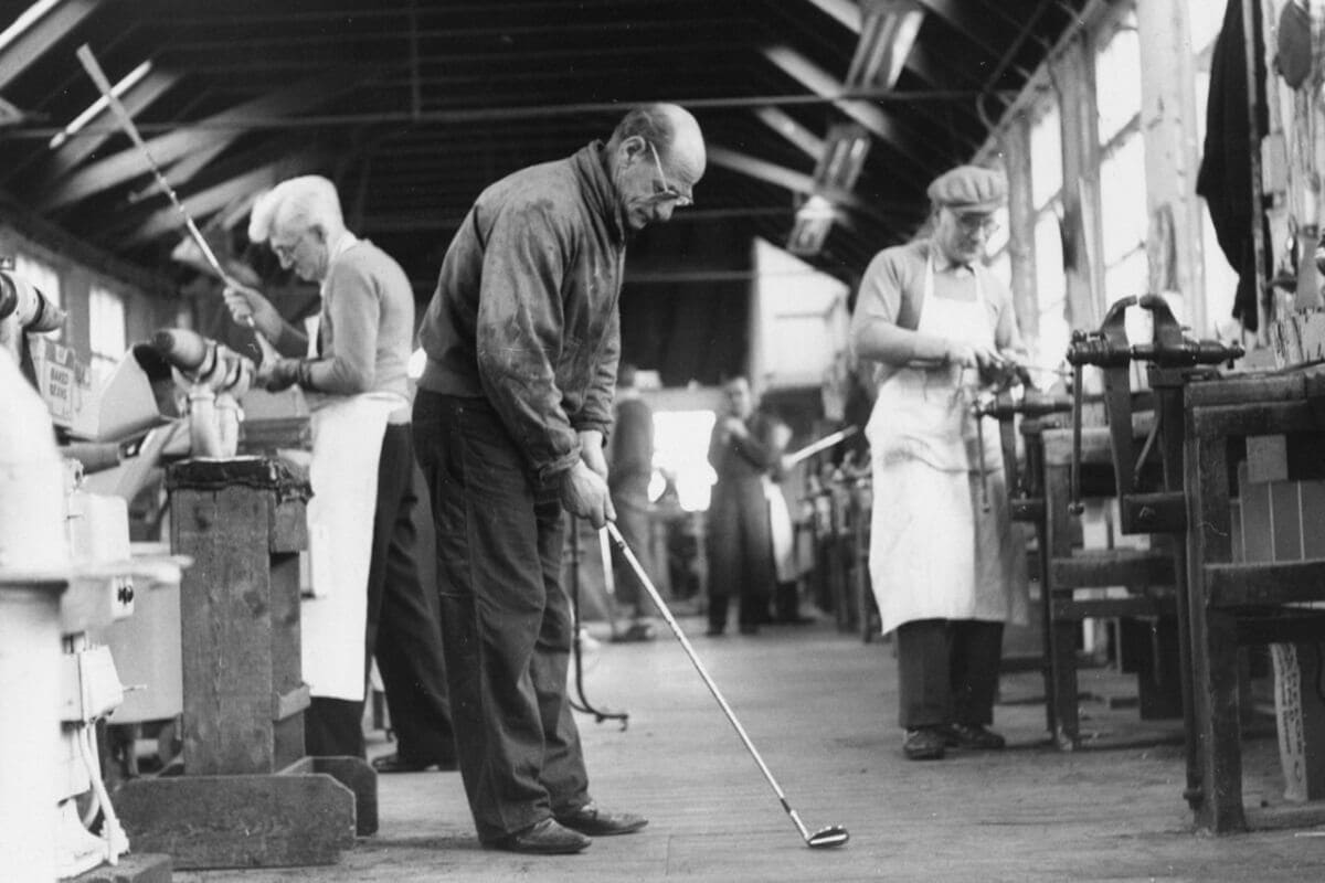 1960年代のスパルディング工房で、職人たちがゴルフクラブを手作業で製作する様子。中央の職人はアイアンをチェックしている。